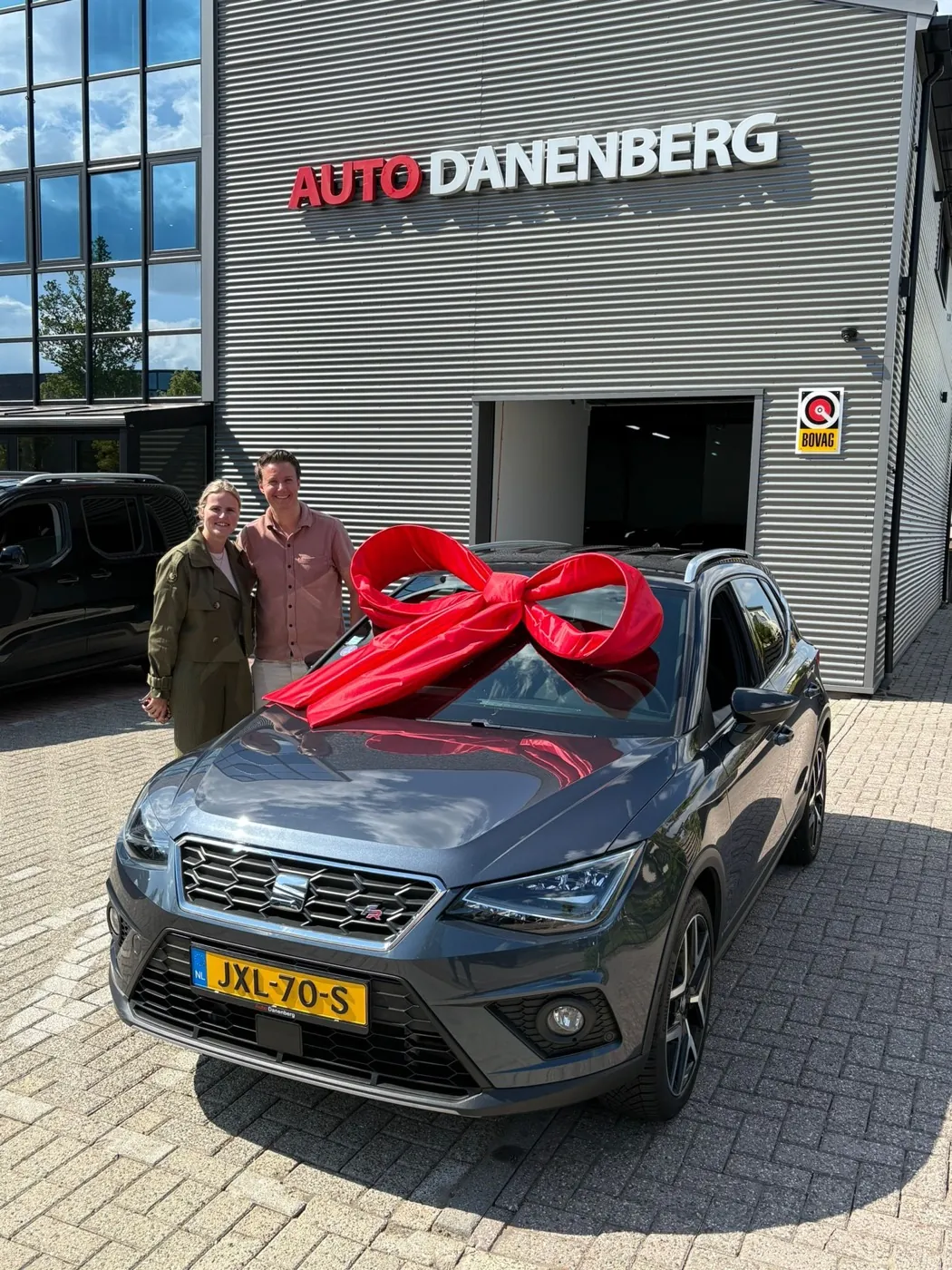 Klanten bij hun nieuwe SEAT met strik voor de showroom van Auto Danenberg